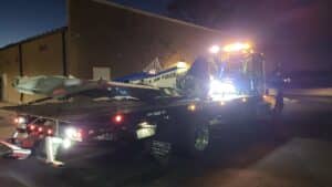 A tow truck carries a small aircraft marked with "U.S. Air Force" in dim light.
